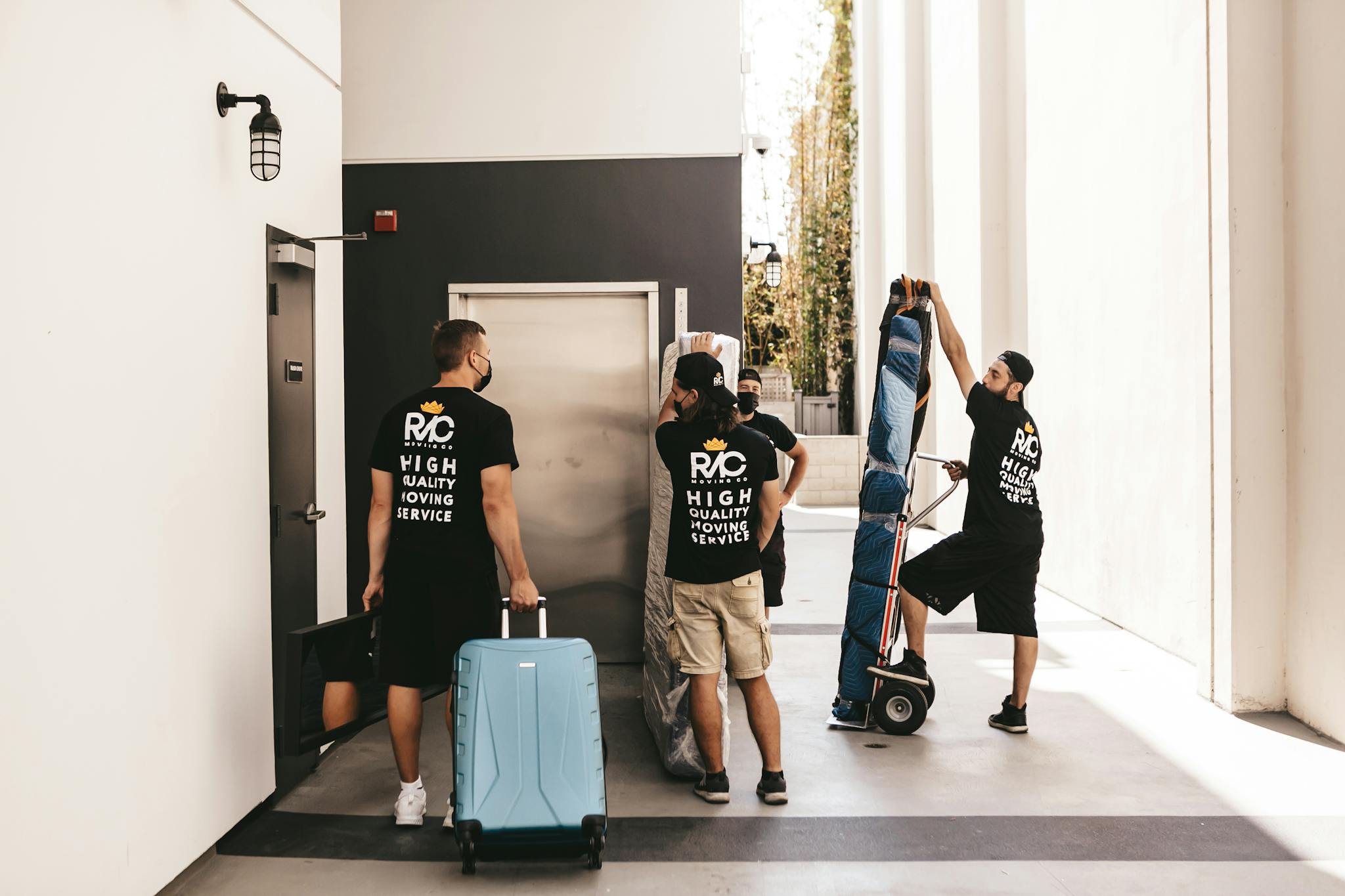 Professional movers transport luggage through an indoor location, showcasing teamwork and efficiency.